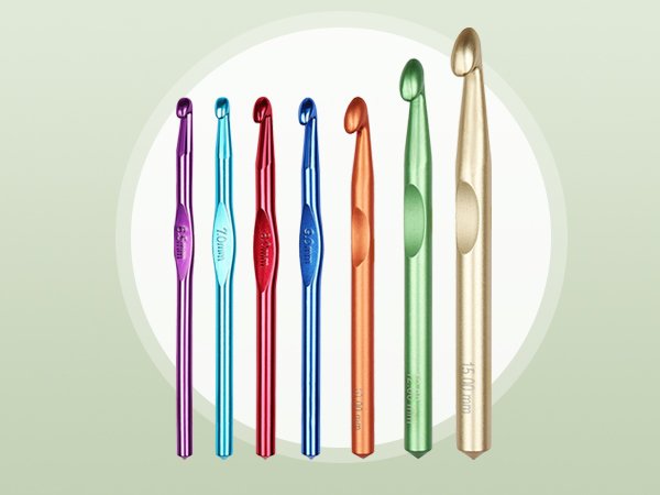 Set of seven crochet hooks with colored handles and marked sizes, displayed on a light green background.
