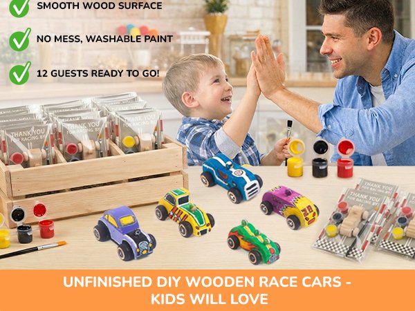 Father and son high-fiving with painted wooden race cars and art supplies on a table