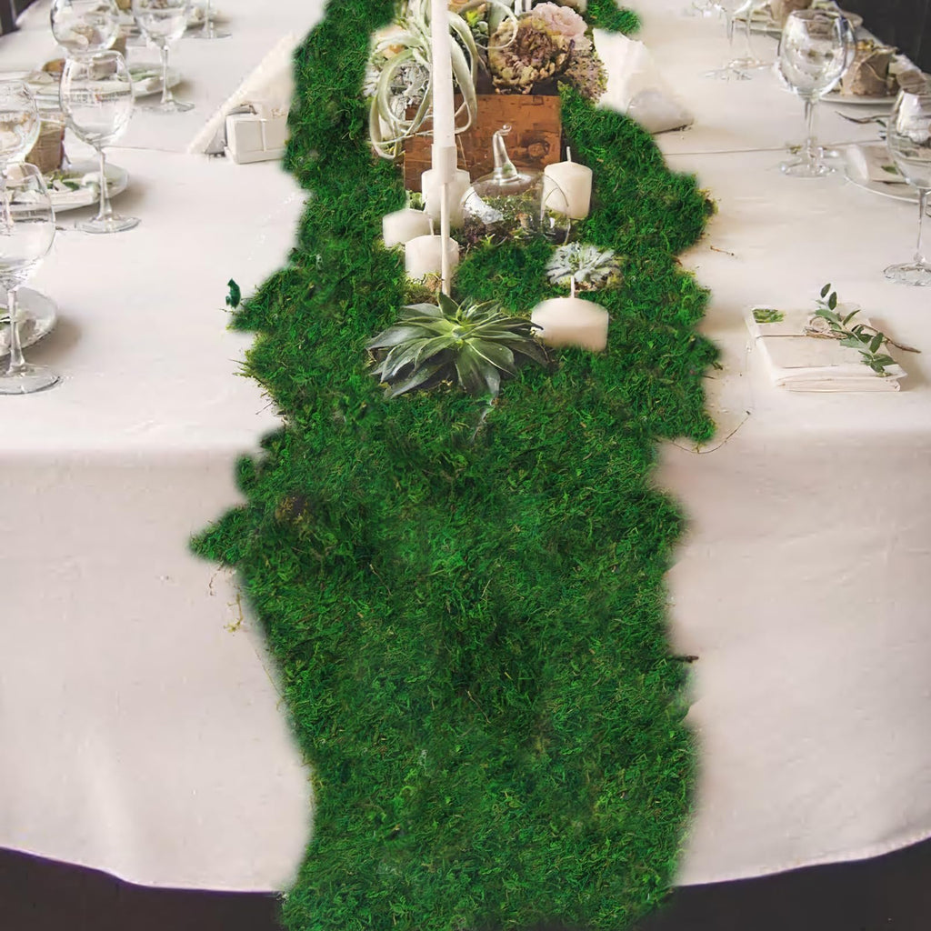 Green moss roll as a table runner with candles and succulents on a white tablecloth