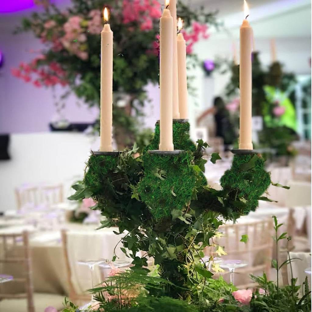 Candlestick centerpiece with moss and greenery on a table at a wedding reception