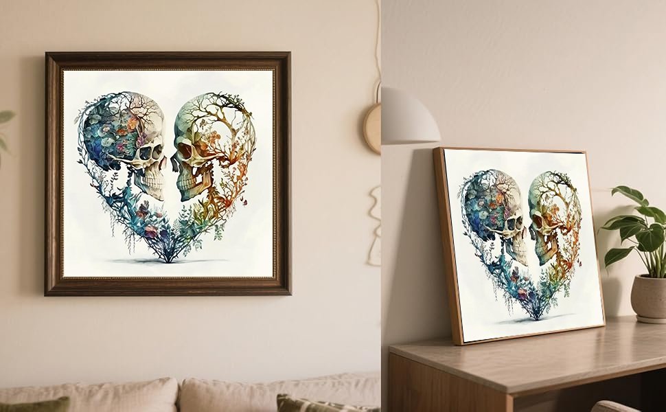 Two framed heart-shaped skull artworks with floral and branch details, displayed on a wall and a table.
