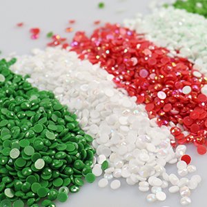 Close-up of four piles of colorful round diamond painting beads: green, white, iridescent white, and red.