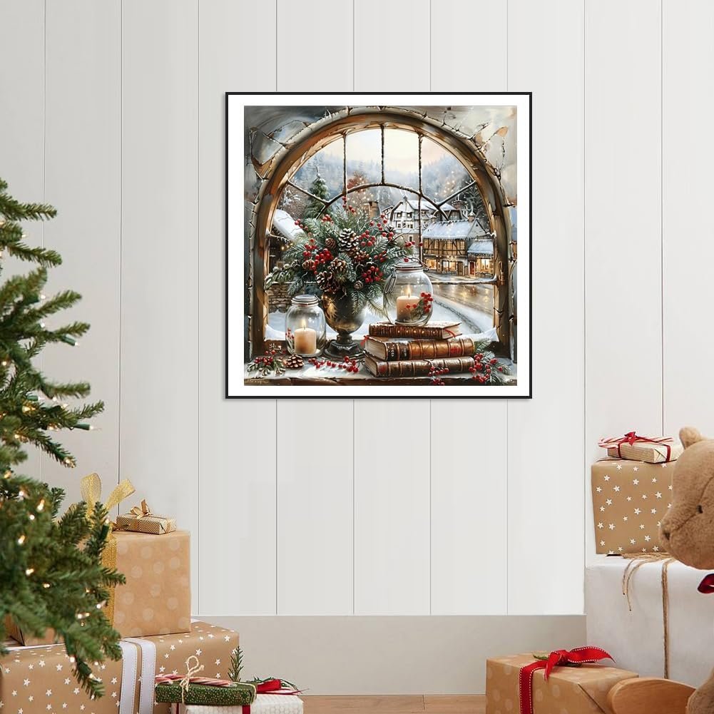 Christmas winter snow landscape diamond painting kit displayed on a shelf with books and candles, viewed through a window.