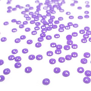 Scattered purple round diamond painting drills on a white background, close-up shot with shallow depth of field.