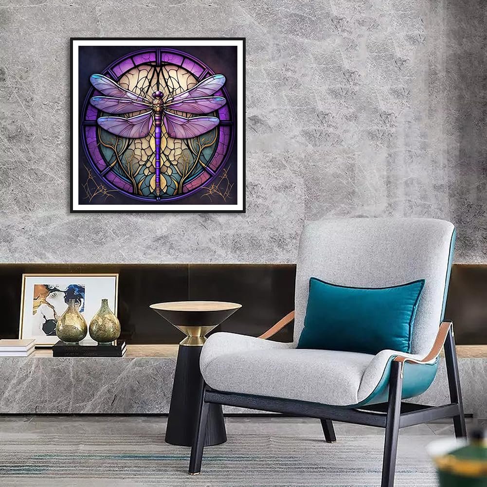 Framed dragonfly diamond painting artwork hanging on a textured wall above a console table with decor and a chair.