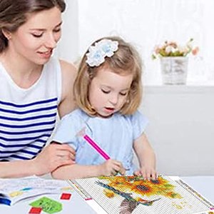 Woman and child doing a diamond painting kit featuring a hummingbird and sunflowers