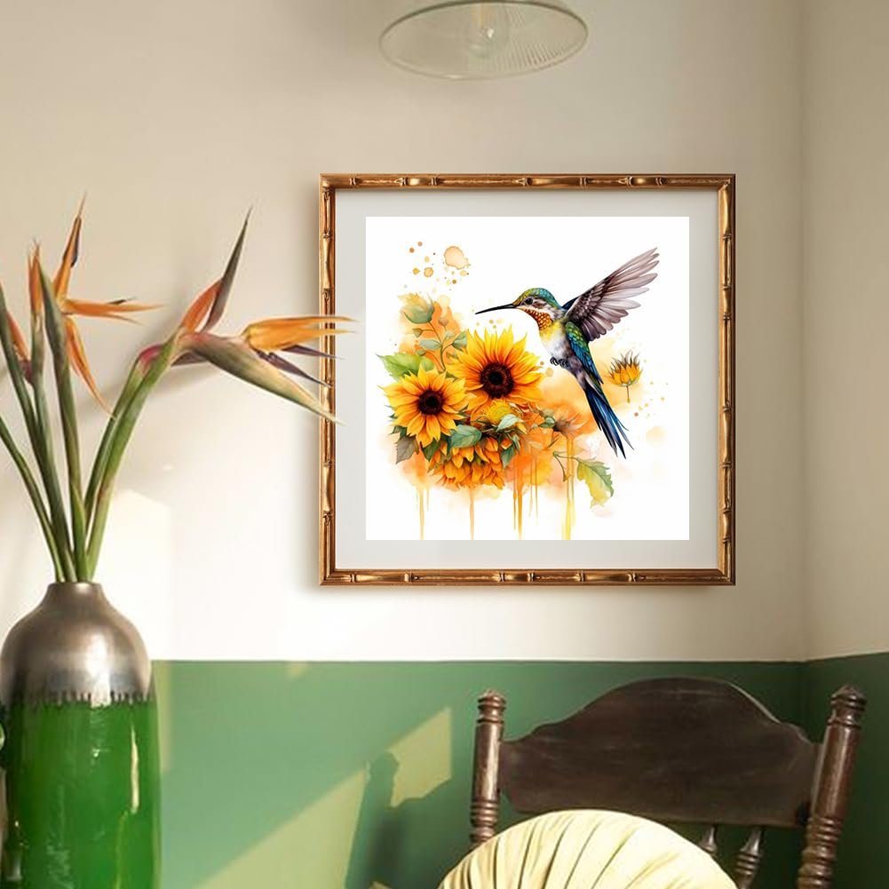 Framed hummingbird and sunflower diamond painting kit artwork hanging on a wall above a chair.