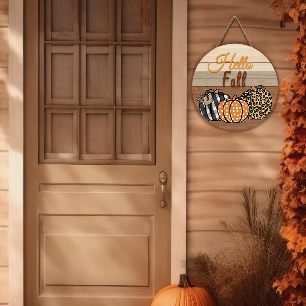 Round wooden fall door sign with pumpkins and 'Hello Fall' text, hanging on a wooden door.