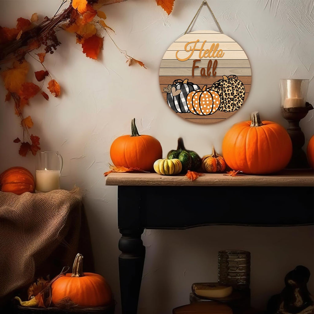 Round wooden fall door sign with pumpkins and 'Hello Fall' text, displayed with real pumpkins and autumn decor.