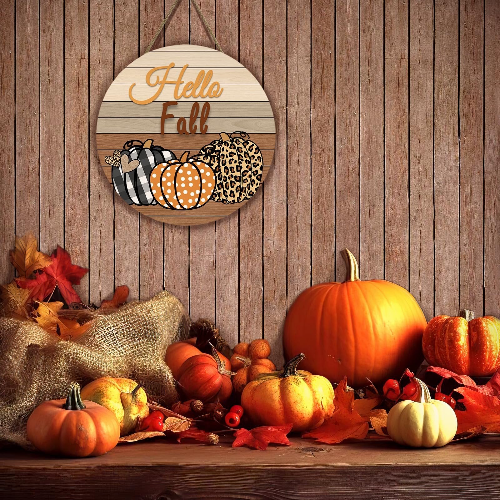 Round wooden fall door sign with pumpkins and 'Hello Fall' text, hanging against a wooden wall with autumn decorations.