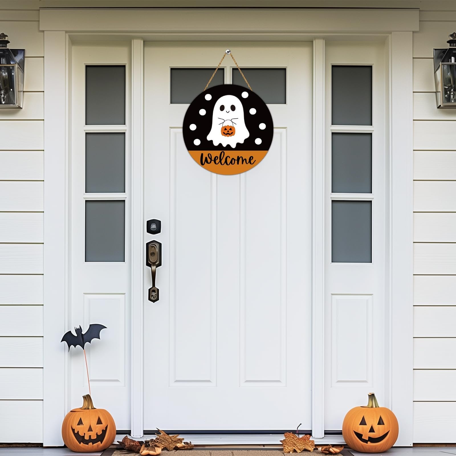 Round Halloween welcome sign with ghost and pumpkin hanging on a white front door.