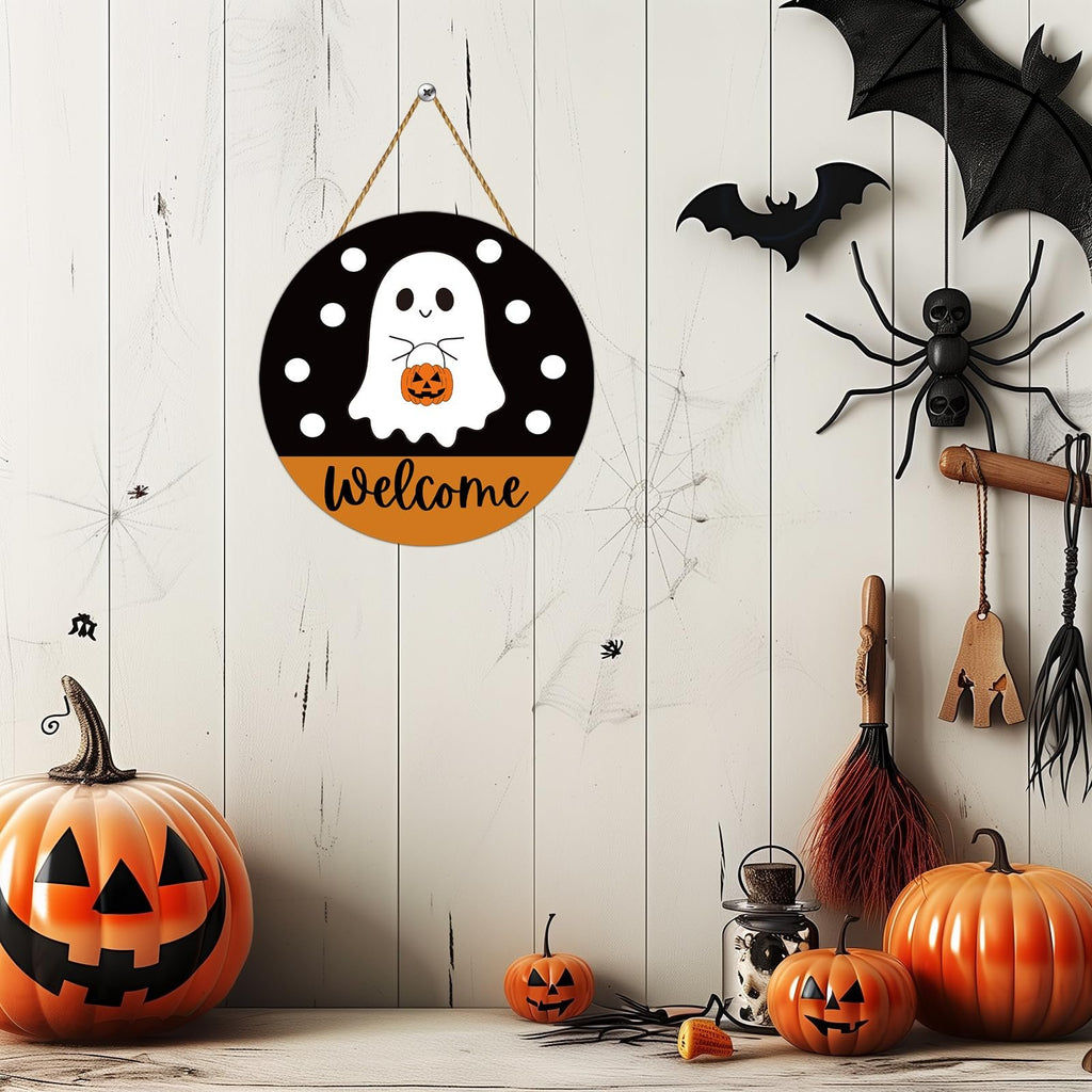 Round Halloween ghost welcome sign with pumpkins and bats, displayed with pumpkins and brooms.