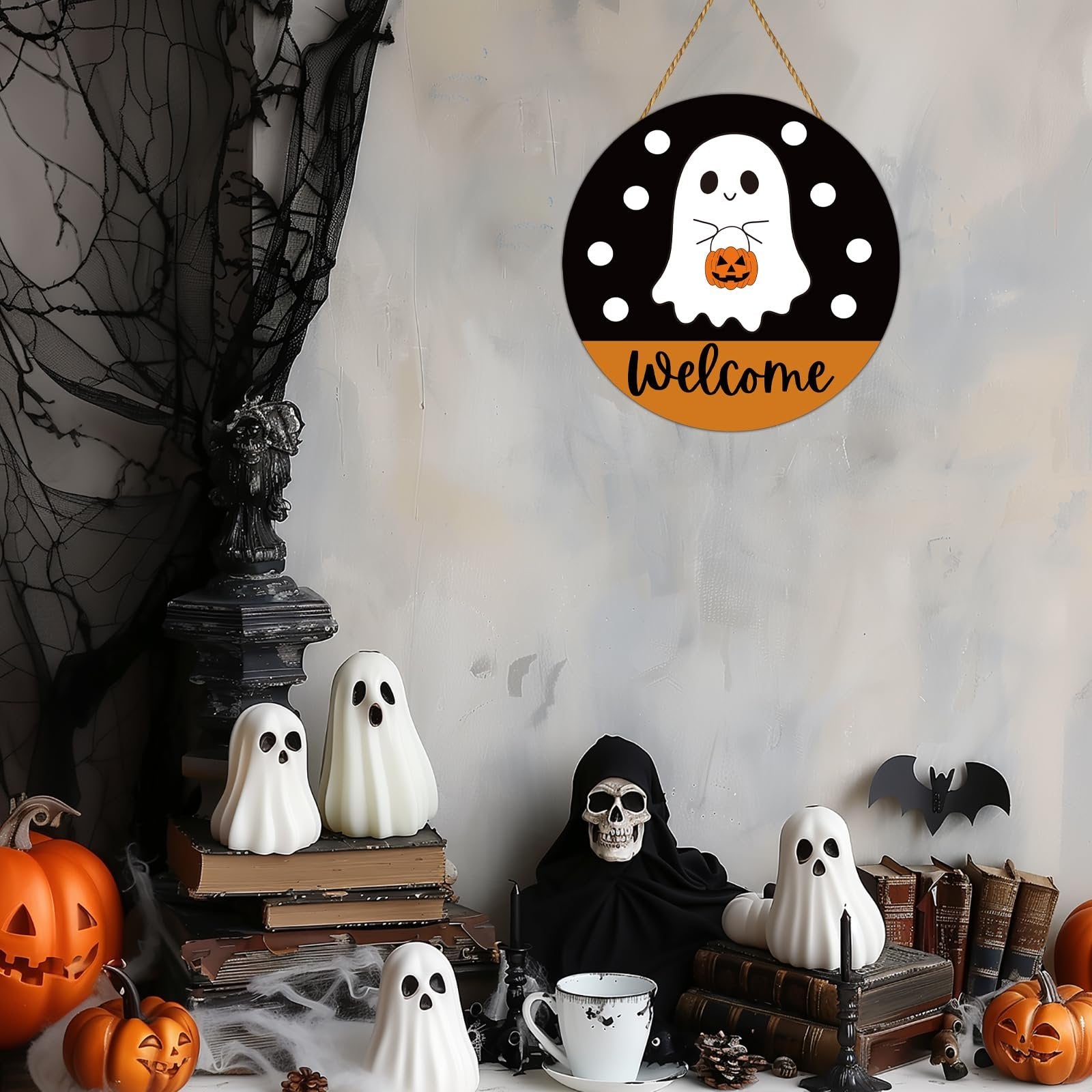 Round Halloween welcome sign with a ghost holding a pumpkin, hanging on a wall with spooky decorations.
