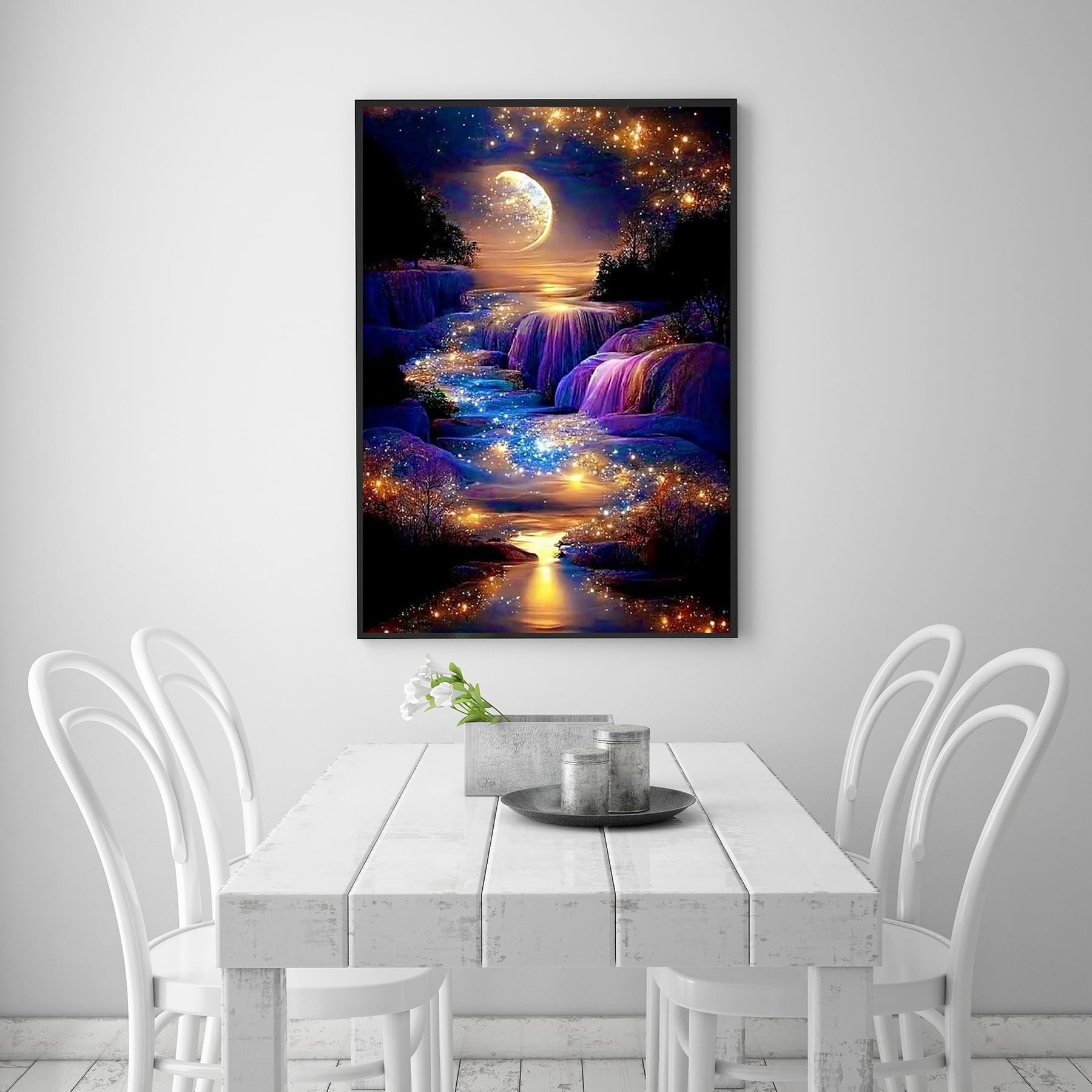 Diamond painting of a moonlit waterfall with sparkling lights, framed and hanging above a white dining table.