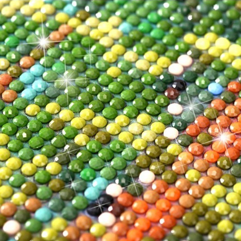 Close-up of a diamond painting kit showing a section of green, yellow, and orange round diamonds arranged in a pattern.