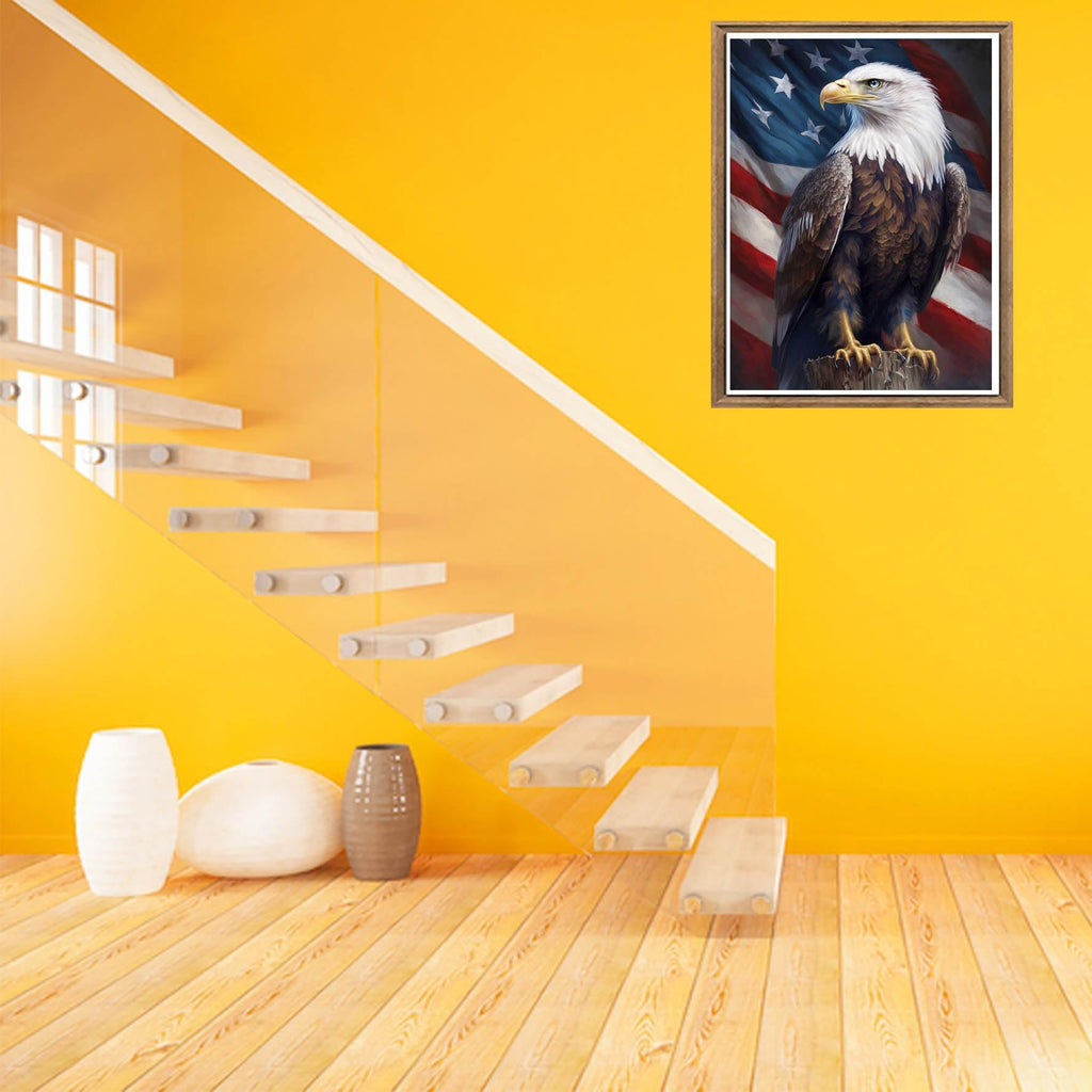 Framed diamond painting of an eagle perched before an American flag, displayed on a yellow wall above a modern staircase and decorative vases.