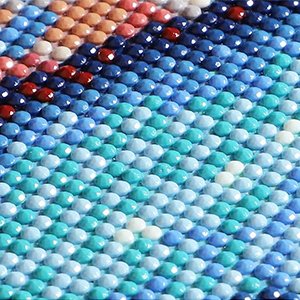 Close-up of a diamond painting kit showing rows of colorful round diamonds forming a landscape pattern.