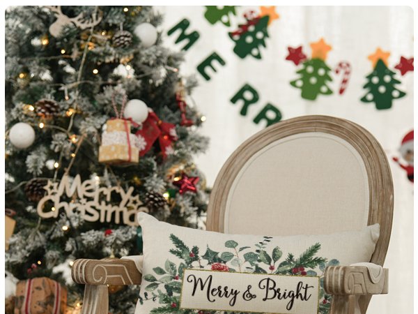 Christmas eucalyptus mistletoe throw pillow cover with 'Merry & Bright' text on a chair next to a decorated Christmas tree.