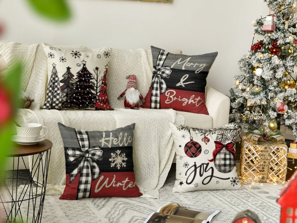 Four Christmas-themed throw pillow covers arranged on a sofa next to a decorated Christmas tree.