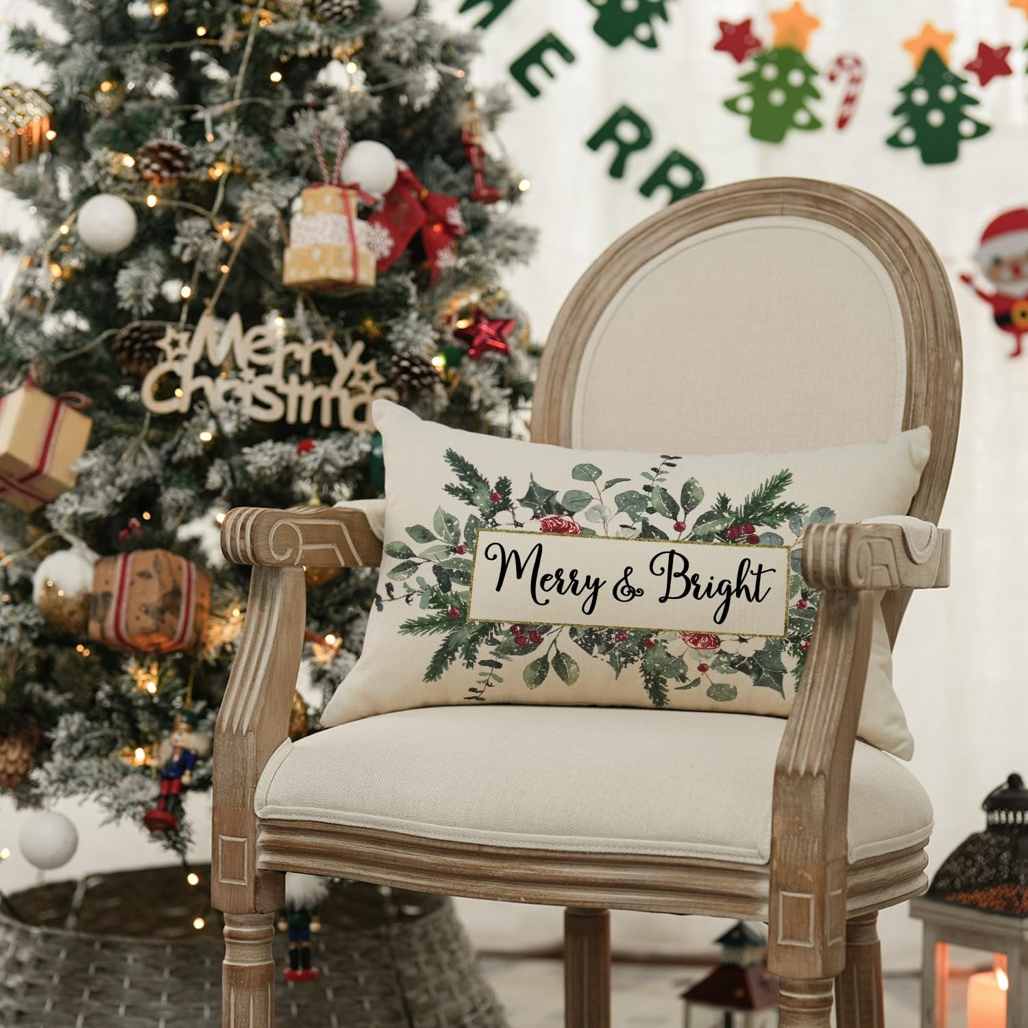 Christmas pillow cover with eucalyptus and mistletoe design on a chair next to a decorated Christmas tree.