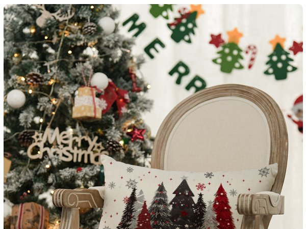Christmas throw pillow cover with red and black trees and snowflakes on a chair next to a decorated tree.