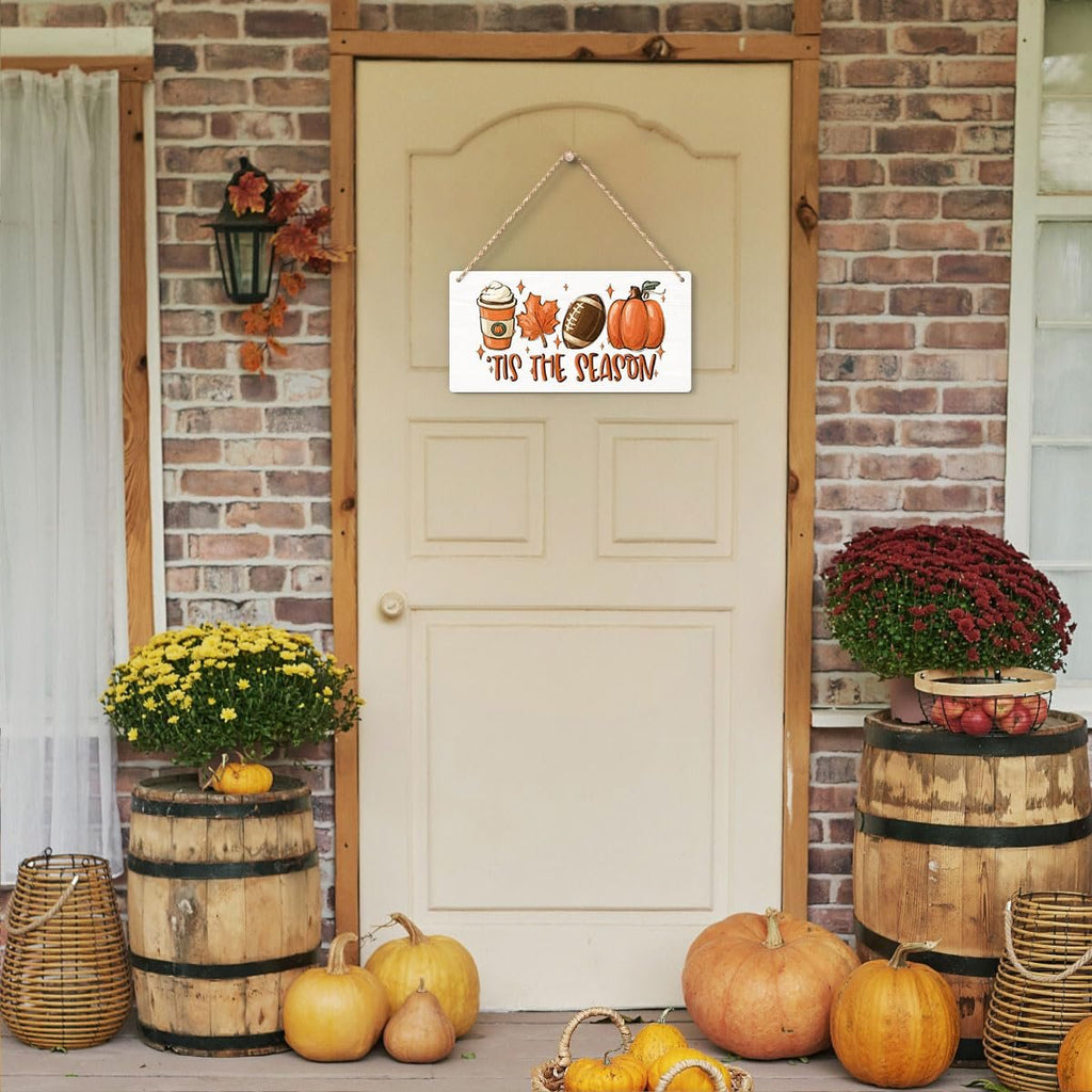 Rectangular wooden fall hanging sign with coffee cup, football, pumpkin, and maple leaves, reading 'Tis the Season, displayed on a door.