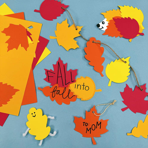Fall leaf paper cutouts arranged as a garland and craft projects, including a hedgehog and a smiling figure.
