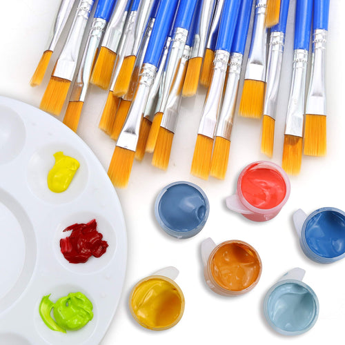 Flat lay of a white paint palette with dollops of yellow, red, and green paint, surrounded by small open pots of blue, orange, and light blue paint, and a large group of nylon paint brushes with blue handles and silver ferrules.