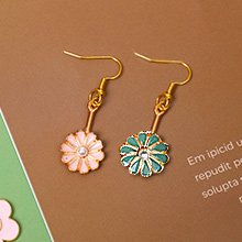 Pair of dangle earrings with flower charms, one pink and one teal, on a brown background.