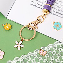 Gold-plated zinc alloy enamel charms including flowers and butterflies, with a keychain and purple tassel.