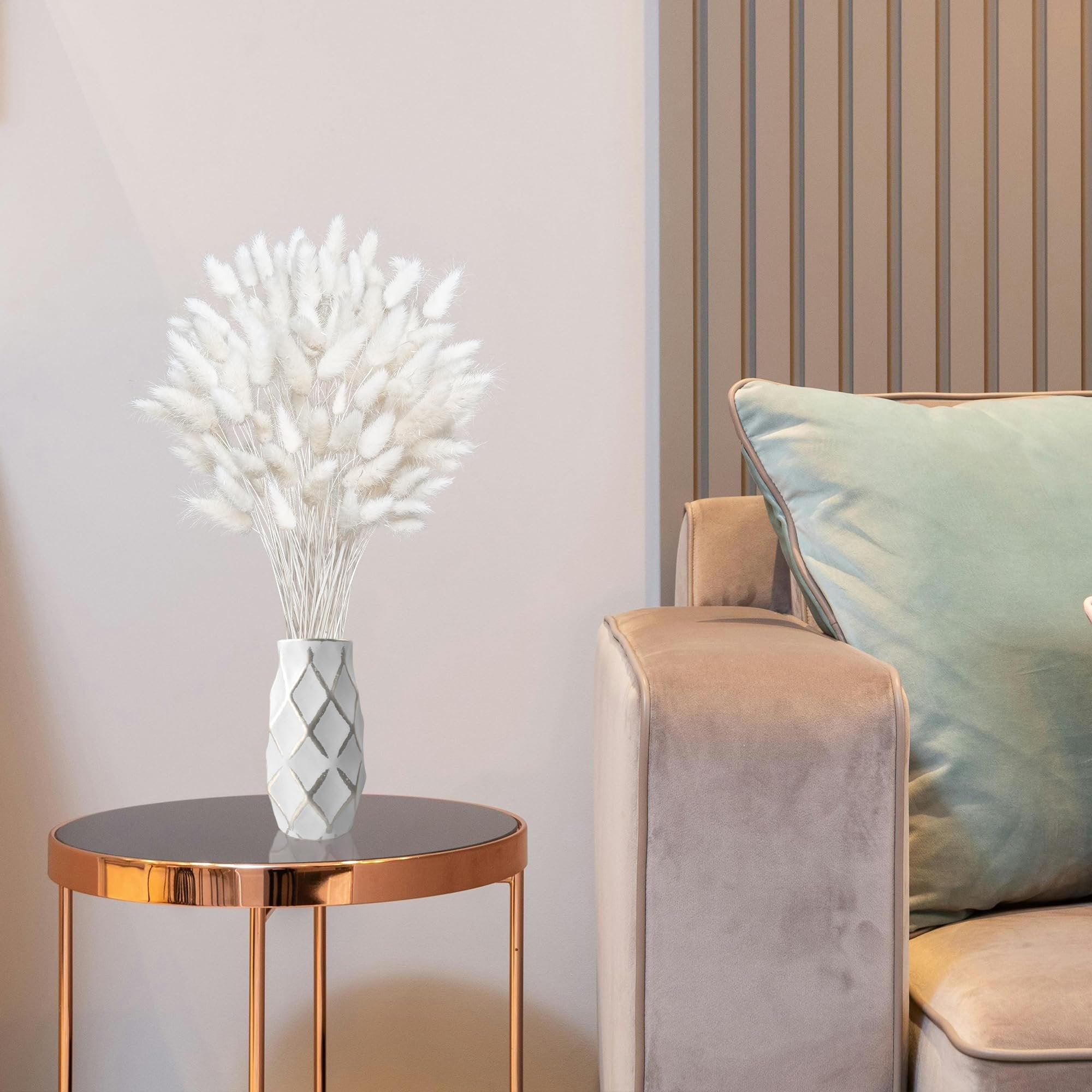 Bouquet of white dried bunny tail grass in a decorative vase on a side table next to a sofa