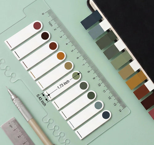 Translucent annotation tabs in various colors laid out with a ruler and pen, showing dimensions.