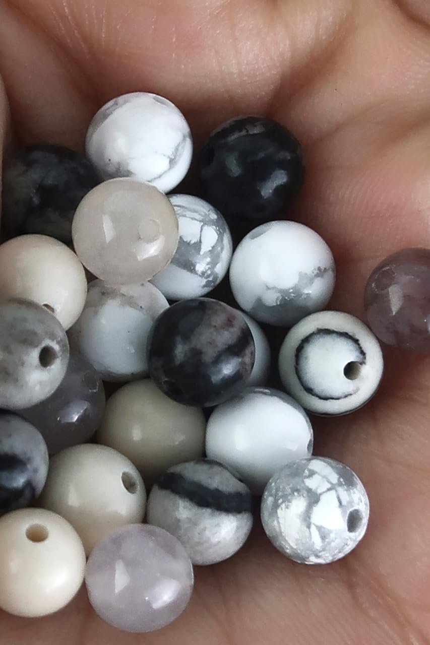 Hand holding a collection of multicolor natural round stone beads with visible holes for jewelry making.