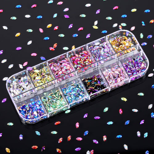 Flat back acrylic horse eye nail rhinestones in 12 rainbow colors, organized in a clear compartment box, scattered on a black background.