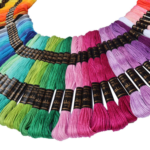Arrangement of colorful embroidery floss skeins in a fan shape, showing shades of yellow, orange, blue, green, pink, and purple. Black labels with gold text are visible on many skeins.