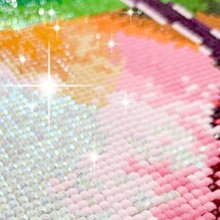 Close-up of a diamond painting with pink, orange, and yellow colors, showing sparkling effects.