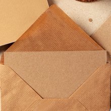 Open brown kraft paper envelope with a blank card inside, flat lay overhead view.
