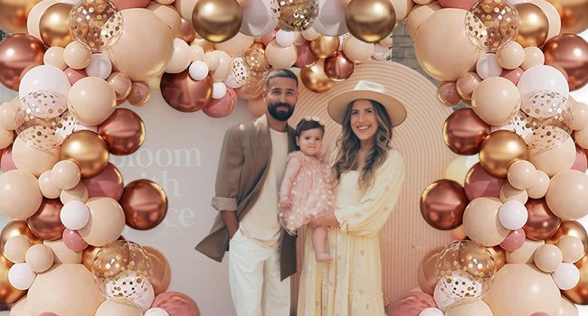 Family posing in a blush and rose gold balloon archway for a celebration