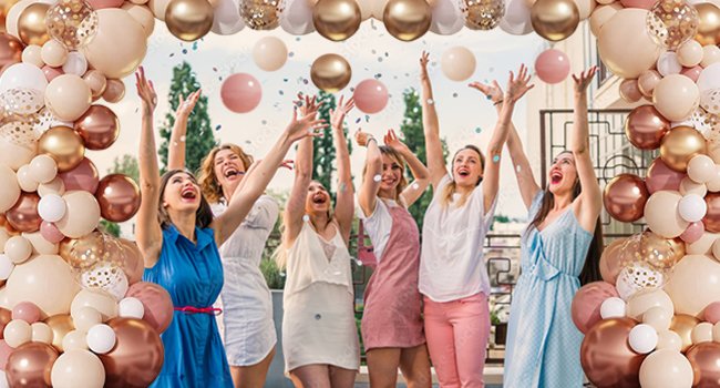 Group of women celebrating with a blush and rose gold balloon garland arch