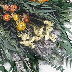 Close-up of a dried floral bouquet featuring eucalyptus, lavender, and yellow and orange dried flowers.