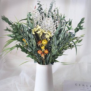 Dried eucalyptus and lavender bouquet with small yellow and orange flowers in a white vase.
