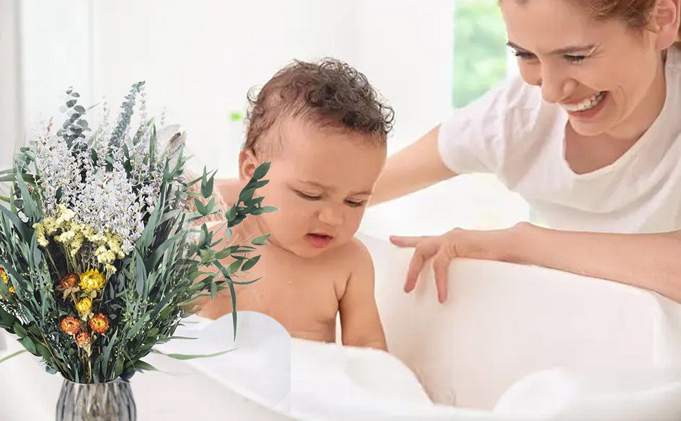 Dried eucalyptus and lavender bouquet next to a baby in a bathtub with a woman smiling