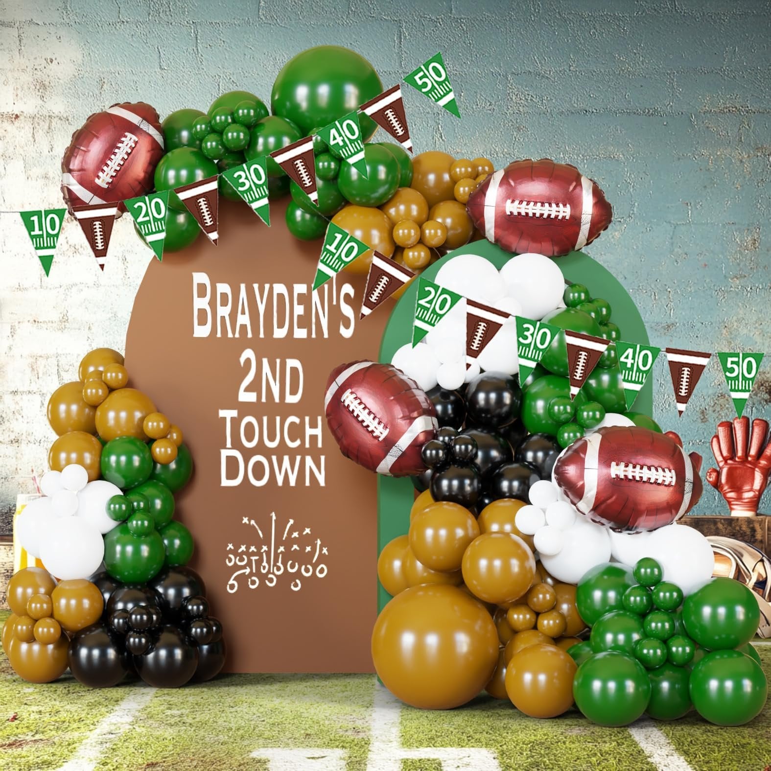 Football-themed balloon arch with footballs, pennant banners showing yard lines, and text 'BRAYDEN'S 2ND TOUCH DOWN'.