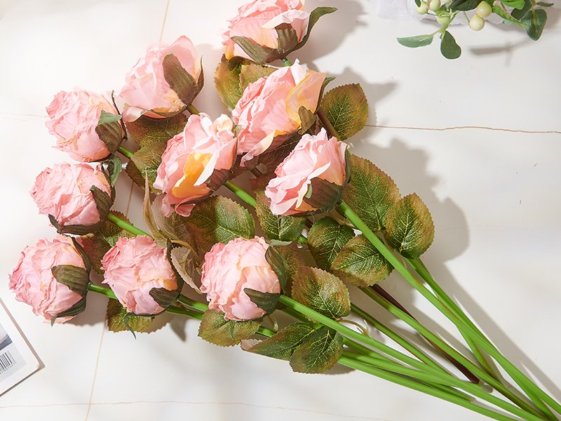 Bunch of 12 pink artificial rose flowers with green stems and leaves, arranged on a white surface.