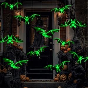 Halloween hanging bats decorations glowing green, arranged on a porch with pumpkins and scarecrows.