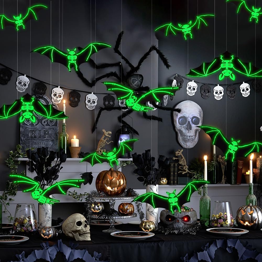Halloween party scene with glowing bats, spider, skulls, and pumpkins on a table and hanging.