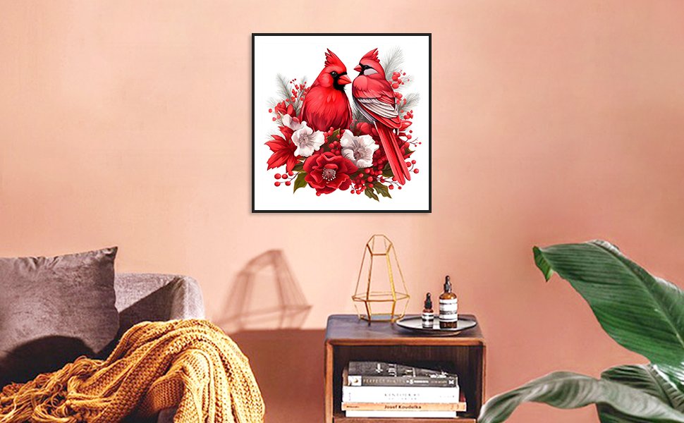 Framed 5D diamond painting of two red cardinals perched among red and white flowers, displayed on a wall above a side table.