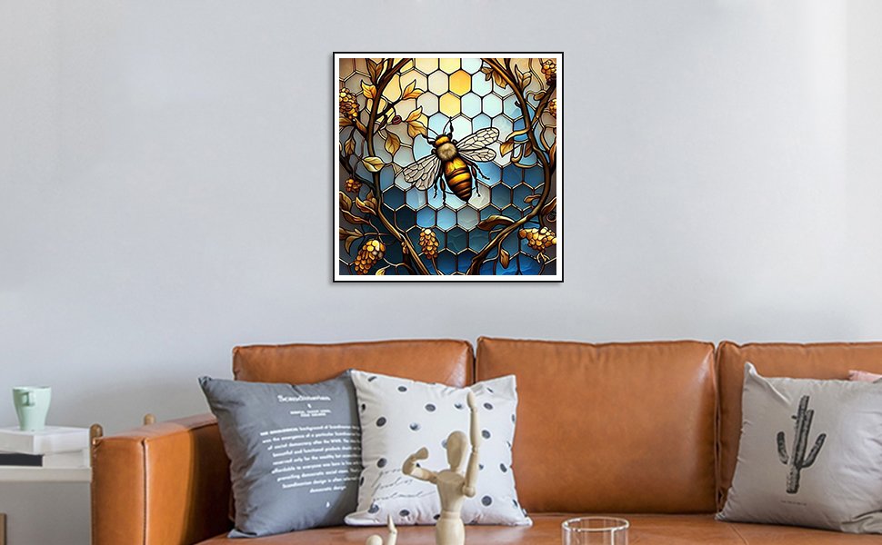 Diamond painting kit featuring a stained glass bee design with honeycomb background, framed and hung above a sofa.