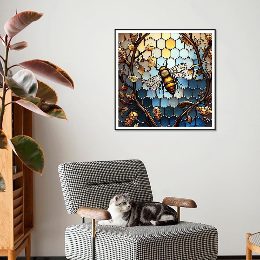 Diamond painting kit featuring a stained glass bee design, framed and displayed in a living room setting with a cat on a chair.
