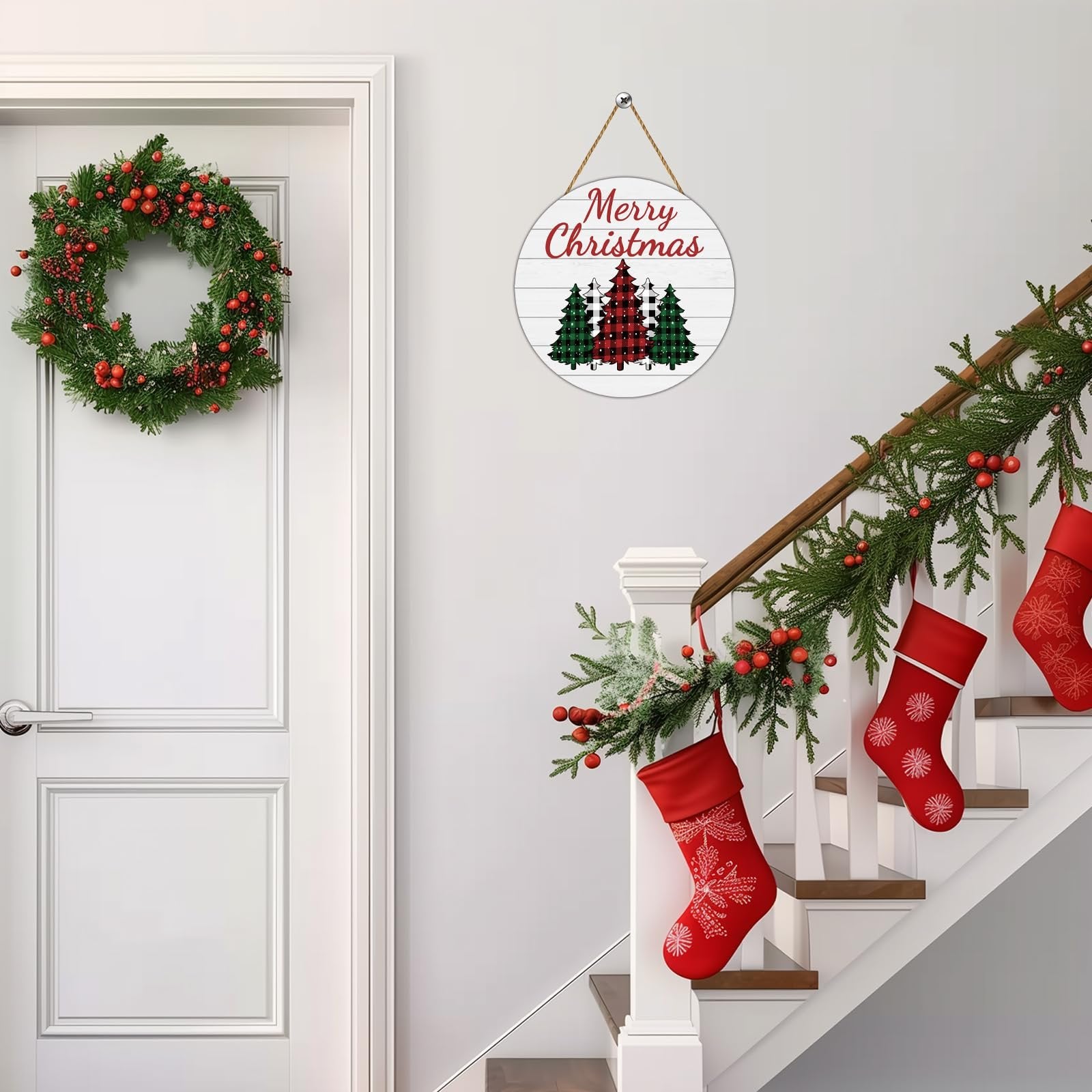 Round buffalo plaid Christmas tree door sign hanging on a wall next to a door with a wreath and a decorated staircase with stockings.